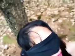Blindfolded brunette slave deepthroats a cock in the woods